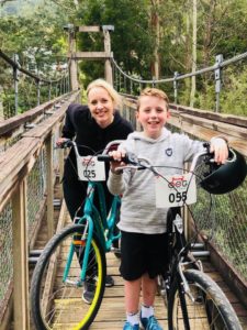 A woman and a boy are standing on a trestle bridge with their bikes.