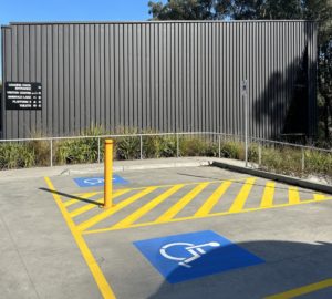 Two accessible car parking spots next to a building with black cladding.